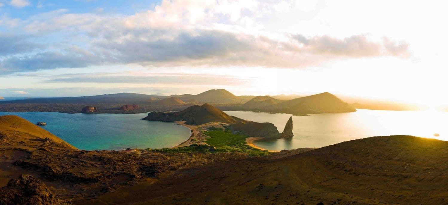 Panoramic view of the Galapagos Islands volcanic landscape with turquoise lagoon at sunset