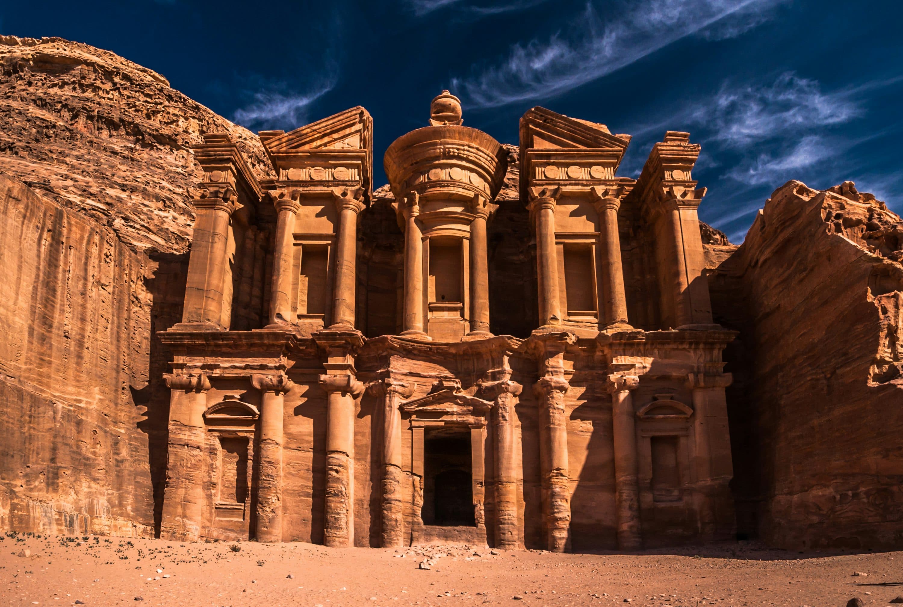 The Monastery at Petra Jordan carved into rose-red sandstone under a deep blue sky